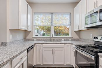 a kitchen with granite counter tops and a window at The Enclave at Crossroads, Raleigh, NC